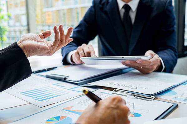 L’image illustre une réunion professionnelle centrée sur l’examen de chiffres, de rapports et d’éléments liés au suivi des factures et des paiements.